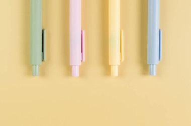 Sarı arka planda renkli kalemlerin üst görüntüsü. Okul, ofis duvar kağıdı. Düz yat, boşluğu kopyala.