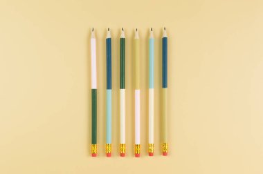 Sarı arka planda renkli kalemlerin üst görüntüsü. Okul, ofis, duvar kâğıdı. Düz yat, boşluğu kopyala.