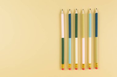 Sarı arka planda renkli kalemlerin üst görüntüsü. Okul, ofis, duvar kâğıdı. Düz yat, boşluğu kopyala.
