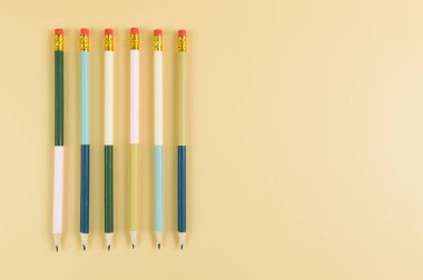 Sarı arka planda renkli kalemlerin üst görüntüsü. Okul, ofis, duvar kâğıdı. Düz yat, boşluğu kopyala.