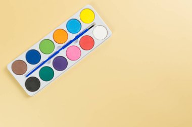 Sarı arka planda suluboya ve boya fırçasının üst görüntüsü. Resim, sanat, kopyalama alanı, düzlük.