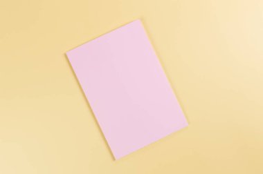 Sarı arkaplanda pembe defterin üst görüntüsü. Okul, ofis duvar kağıdı. Düz yat, boşluğu kopyala.