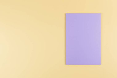 Sarı arkaplanda mor defterin üst görüntüsü. Okul, ofis duvar kağıdı. Düz yat, boşluğu kopyala.