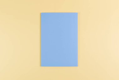 Sarı arkaplanda mavi defterin üst görüntüsü. Okul, ofis duvar kağıdı. Düz yat, boşluğu kopyala.