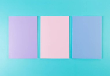 Mavi arka planda pembe, mor ve mavi defterlerin üst görüntüsü. Okul, ofis duvar kağıdı. Düz yat, boşluğu kopyala.