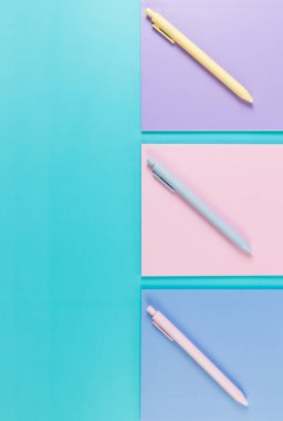 Mavi arka planda pembe, mor ve mavi defterlerin üst görüntüsü. Pembe, sarı ve mavi kalemler, okul, ofis kağıdı. Düz yat, boşluğu kopyala.