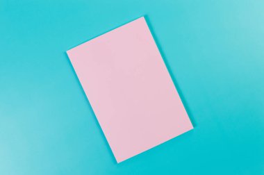 Mavi arkaplanda pembe defterin üst görüntüsü. Okul, ofis duvar kağıdı. Düz yat, boşluğu kopyala.