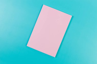 Mavi arkaplanda pembe defterin üst görüntüsü. Okul, ofis duvar kağıdı. Düz yat, boşluğu kopyala.