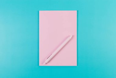Pembe defterin üst görüntüsü, mavi arka planda pembe kalem. Okul, ofis duvar kağıdı. Düz yat, boşluğu kopyala.