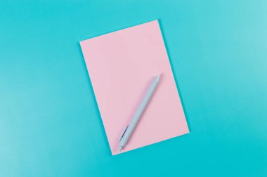 Pembe defterin üst görüntüsü, mavi arka planda mavi kalem. Okul, ofis duvar kağıdı. Düz yat, boşluğu kopyala.