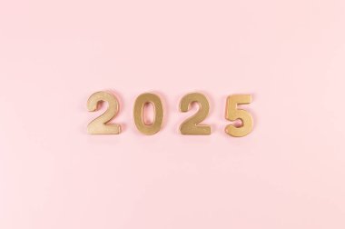 2025 mutlu yıllar. Pembe arka planda altın rakamların üst görüntüsü. Uzayı kopyala, düz yat.