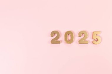 2025 mutlu yıllar. Pembe arka planda altın rakamların üst görüntüsü. Uzayı kopyala, düz yat.