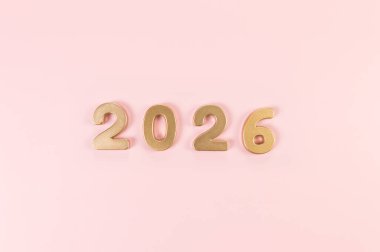 2026 mutlu yıllar. Pembe arka planda altın rakamların üst görüntüsü. Uzayı kopyala, düz yat.