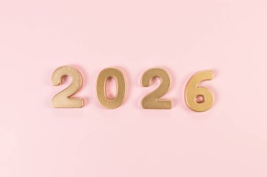 2026 mutlu yıllar. Pembe arka planda altın rakamların üst görüntüsü. Uzayı kopyala, düz yat.