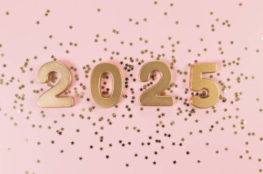 2025 mutlu yıllar. Altın sayılar manzarası, pembe arka planda altın yıldızlı konfeti. Uzayı kopyala, düz yat.
