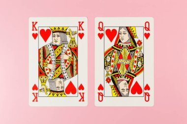 Pembe arka planda kart oynamanın en üst görüntüsü. Kral ve kraliçe, iki kart, masa oyunu, poker. Uzayı kopyala, düz yat.