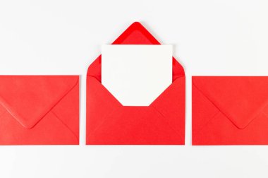 Kırmızı zarfların üst görüntüsü, beyaz arka planda beyaz kart. Yat yere. Boşluğu kopyala.