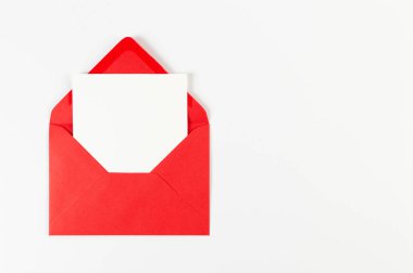Kırmızı zarfın üst görüntüsü, beyaz arka planda beyaz kart. Yat yere. Boşluğu kopyala.
