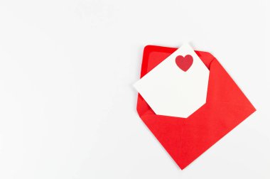 Kırmızı zarfın üst görüntüsü, beyaz arka planda beyaz kart. Sevgililer günü, kırmızı kalp, aşk. Düz yatay, kopyala boşluk.