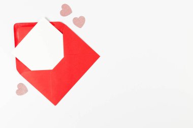 Kırmızı zarfın üst görüntüsü, beyaz arka planda beyaz kart. Sevgililer günü, pembe parıltılı kalpler, aşkım. Düz yatay, kopyala boşluk.