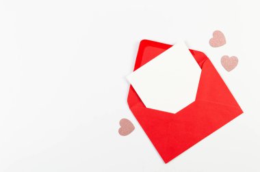 Kırmızı zarfın üst görüntüsü, beyaz arka planda beyaz kart. Sevgililer günü, pembe parıltılı kalpler, aşkım. Düz yatay, kopyala boşluk.