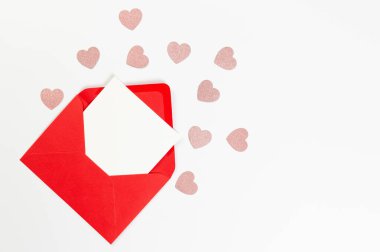 Kırmızı zarfın üst görüntüsü, beyaz arka planda beyaz kart. Sevgililer günü, pembe parıltılı kalpler, aşkım. Düz yatay, kopyala boşluk.