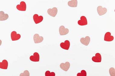 Beyaz arka planda kırmızı ve pembe parıltılı kalplerin üst görüntüsü. Sevgililer günü, pembe parlak kalpler, kırmızı kalpler, aşk duvar kağıtları. Düz yat, boşluğu kopyala.