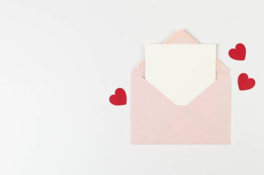 Pembe zarfın üst görüntüsü, beyaz arka planda beyaz kart. Sevgililer günü, kırmızı kalpler, aşk. Düz yatay, kopyala boşluk.