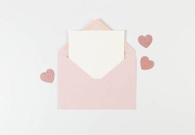 Pembe zarfın üst görüntüsü, beyaz arka planda beyaz kart. Sevgililer günü, pembe parıltılı kalpler, aşkım. Düz yatay, kopyala boşluk.