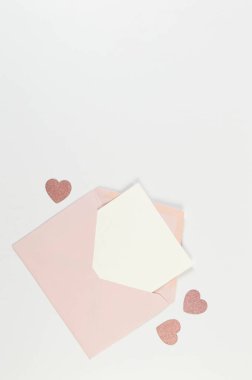 Pembe zarfın üst görüntüsü, beyaz arka planda beyaz kart. Sevgililer günü, pembe parıltılı kalpler, aşkım. Düz yatay, kopyala boşluk.