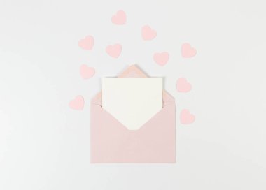 Pembe zarfın üst görüntüsü, beyaz arka planda beyaz kart. Sevgililer günü, pembe kalpler, aşk. Düz yatay, kopyala boşluk.