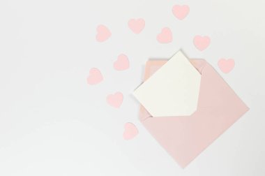 Pembe zarfın üst görüntüsü, beyaz arka planda beyaz kart. Sevgililer günü, pembe kalpler, aşk. Düz yatay, kopyala boşluk.