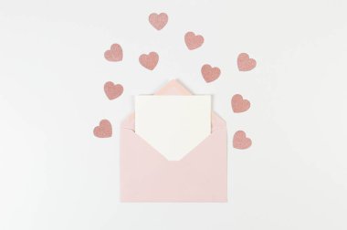 Pembe zarfın üst görüntüsü, beyaz arka planda beyaz kart. Sevgililer günü, pembe parıltılı kalpler, aşkım. Düz yatay, kopyala boşluk.