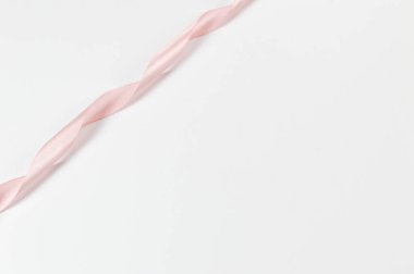 Beyaz arka planda pembe kurdelenin üst görüntüsü. Parlak rulo kumaş, ipek ve saten kumaş. Boşluğu kopyala.