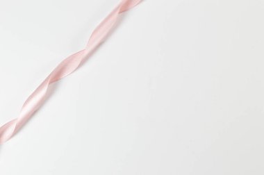 Beyaz arka planda pembe kurdelenin üst görüntüsü. Parlak rulo kumaş, ipek ve saten kumaş. Boşluğu kopyala.