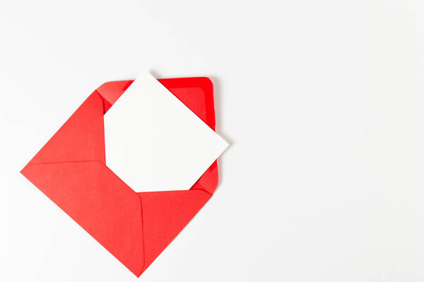 Top view of red envelope, white card on white background. Post flat lay. Copy space.