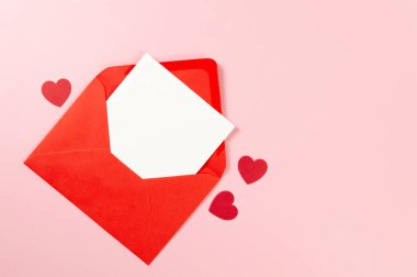 Kırmızı zarfın üst görüntüsü, pembe arka planda beyaz kart. Sevgililer günü, kırmızı kalpler, aşk. Düz yatay, kopyala boşluk.