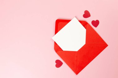 Kırmızı zarfın üst görüntüsü, pembe arka planda beyaz kart. Sevgililer günü, kırmızı kalpler, aşk. Düz yatay, kopyala boşluk.