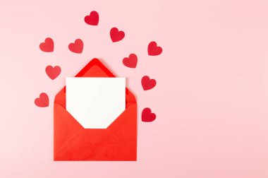 Kırmızı zarfın üst görüntüsü, pembe arka planda beyaz kart. Sevgililer günü, kırmızı kalpler, aşk. Düz yatay, kopyala boşluk.