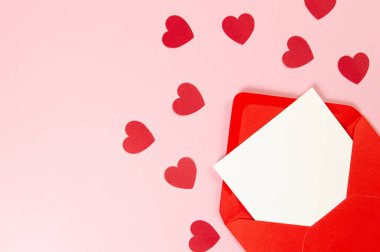 Kırmızı zarfın üst görüntüsü, pembe arka planda beyaz kart. Sevgililer günü, kırmızı kalpler, aşk. Düz yatay, kopyala boşluk.