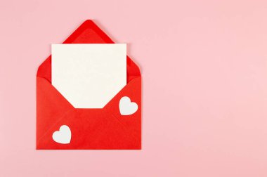 Kırmızı zarfın üst görüntüsü, pembe arka planda beyaz kart. Sevgililer günü, beyaz kalpler, aşk. Düz yatay, kopyala boşluk.