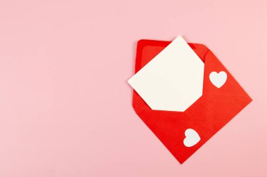 Kırmızı zarfın üst görüntüsü, pembe arka planda beyaz kart. Sevgililer günü, beyaz kalpler, aşk. Düz yatay, kopyala boşluk.