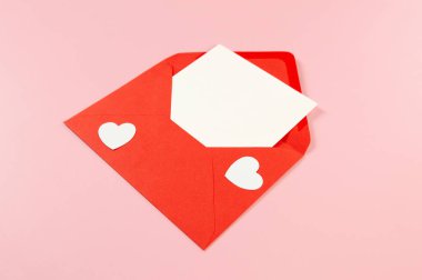 Kırmızı zarfın üst görüntüsü, pembe arka planda beyaz kart. Sevgililer günü, beyaz kalpler, aşk. Düz yatay, kopyala boşluk.