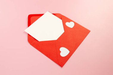 Kırmızı zarfın üst görüntüsü, pembe arka planda beyaz kart. Sevgililer günü, beyaz kalpler, aşk. Düz yatay, kopyala boşluk.