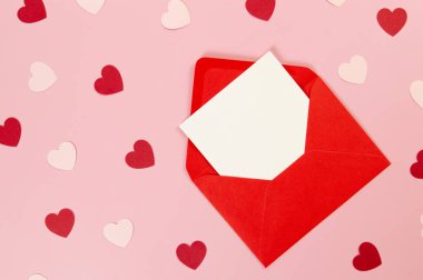 Kırmızı zarfın üst görüntüsü, pembe arka planda beyaz kart. Pembe kalpler, kırmızı kalpler. Sevgililer Günü, aşkım. Düz yatay, kopyala boşluk.