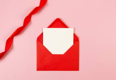 Kırmızı zarfın üst görüntüsü, beyaz kart ve pembe arka planda kırmızı kurdele. Sevgililer Günü, aşkım. Parlak rulo kumaş, ipek ve saten kumaş. Boşluğu kopyala, düzleştir, gönder.