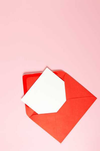 Top view of red envelope, white card on pink background. Post flat lay. Copy space.