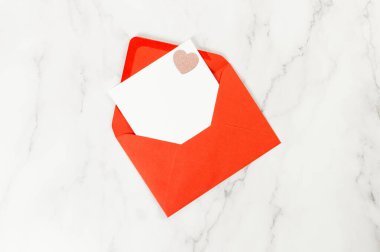 Kırmızı zarfın üst görüntüsü, beyaz mermer arka planda beyaz kart. Sevgililer günü, pembe pırıltılı kalp, aşkım. Düz yatay, kopyala boşluk.