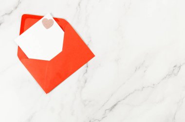 Kırmızı zarfın üst görüntüsü, beyaz mermer arka planda beyaz kart. Sevgililer günü, pembe pırıltılı kalp, aşkım. Düz yatay, kopyala boşluk.