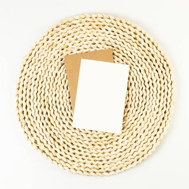 Kahverengi hasır masa paspasının üst görüntüsü, beyaz arka planda beyaz ve kahverengi kartlar. Saman yuvarlak tepsi, düz konum, kopyalama alanı. 